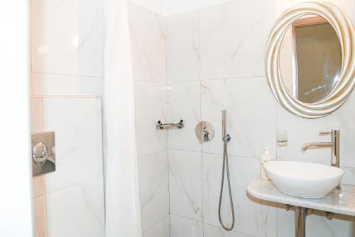 bagno con doccia, lavandino e specchio di Villa Maina a Kamari