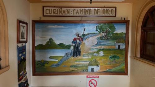 a painting on a wall with a sign on it at Hostal Curiñan in Otavalo