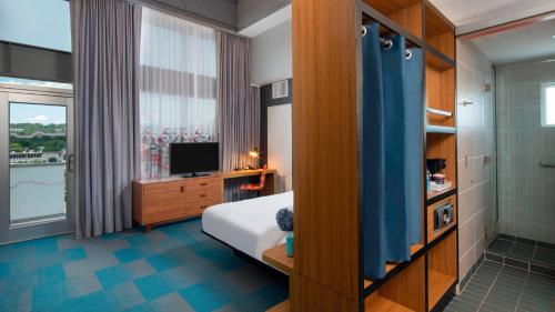 a bedroom with a bed and a desk and a television at Aloft Birmingham Soho Square in Homewood