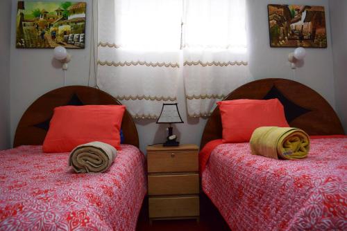two beds in a bedroom with red pillows at Carlos Guest House 1 Cusco in Cusco