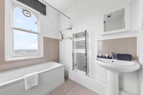 a white bathroom with a sink and a bath tub and a window at The Earl - Hampstead Heath in London