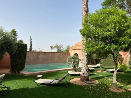 a backyard with a swimming pool and chairs and trees at Villa #1 ‘Rosalie’ in Marrakech