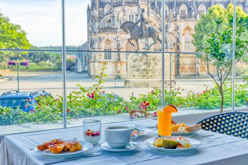 a table with plates of food and a view of a building at Hotel Lis Batalha in Batalha