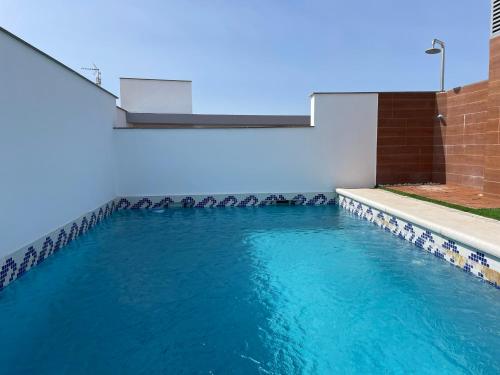 a swimming pool with blue water in a building at Casa Yaye Écija in Écija