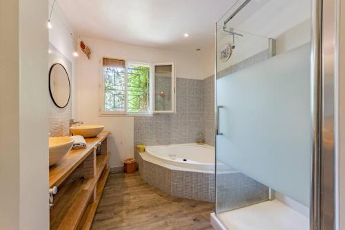 une salle de bain avec baignoire et douche en verre dans l'établissement La Quiétude, maison paisible avec piscine, à Moissac