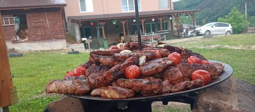 een bord vlees en worst op een grill bij Casa Găleată in Nehoiu
