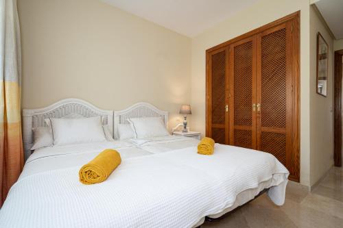 1 dormitorio con 1 cama blanca grande y 2 almohadas amarillas en Costalita Beach Apartment, en Estepona
