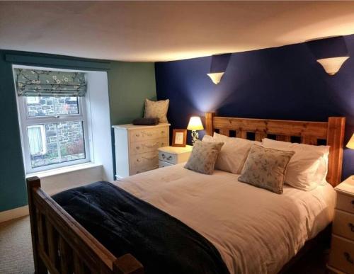una camera da letto con un letto grande con una parete blu di Glasfor Cottage a Llwyngwril