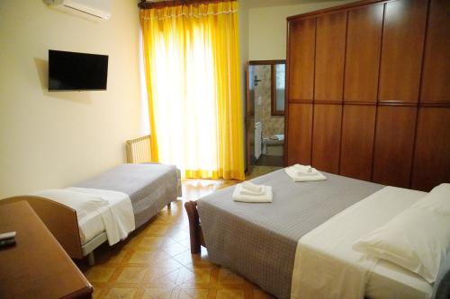 Cette chambre comprend 2 lits et une fenêtre. dans l'établissement Villa Rosa a 50mt dal mare, à Gabicce Mare