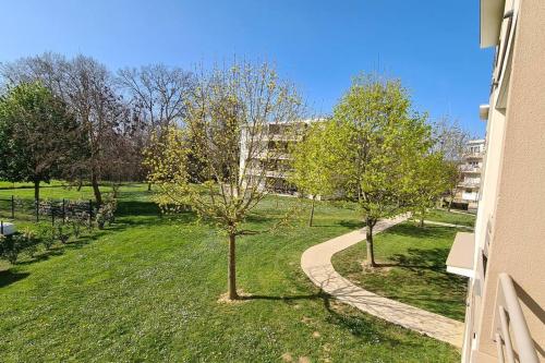 a path through a park with trees and a building at Appartement Proche DisneyLand Paris in Montévrain
