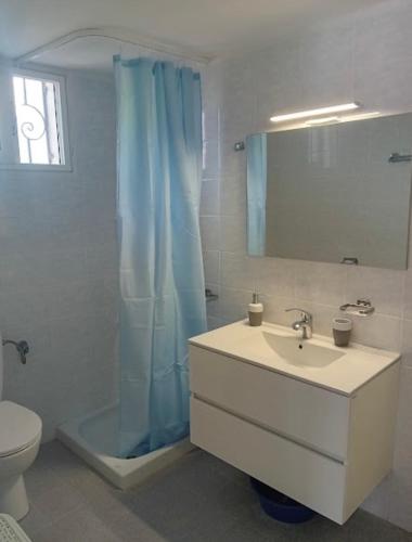 a bathroom with a blue shower curtain and a sink at By the sea dome in Maronia