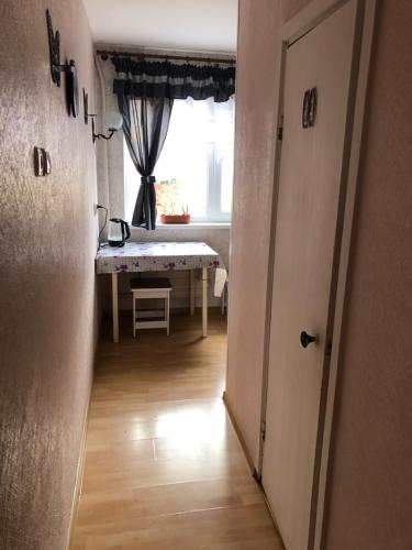 un couloir avec une chambre dotée d'une table et d'une fenêtre dans l'établissement Maleva apartaments, à Kohtla-Järve