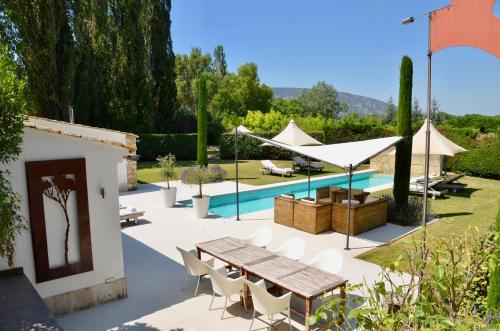 un patio con mesa, sillas y piscina en LASUITE Domaine Bertuli, heated Pool, Aircon en Oppède