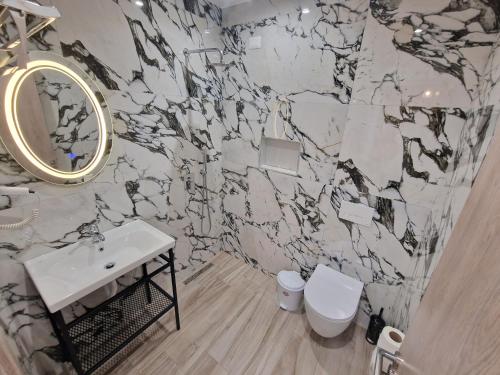 a bathroom with a white sink and a marble wall at Joanna Suites in Sarandë