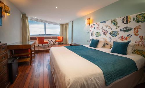a hotel room with a large bed and a desk at LOGIS HOTEL - La Petite Rade in Le Havre