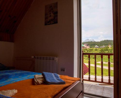 een slaapkamer met een bed en een groot raam bij Moticki Gaj Cottage in Žabljak