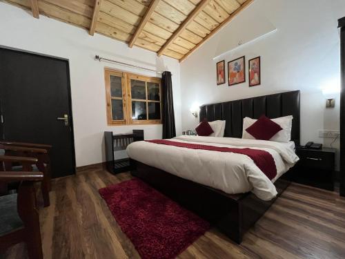 Un dormitorio con una cama grande y una alfombra roja en Cedar Woods Resort, en Nainital
