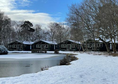 una casa en la nieve junto a un cuerpo de agua en Great Wood Lodges, en Flaxton