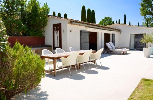 a patio with a wooden table and white chairs at LASUITE Domaine Bertuli, heated Pool, Aircon in Oppède