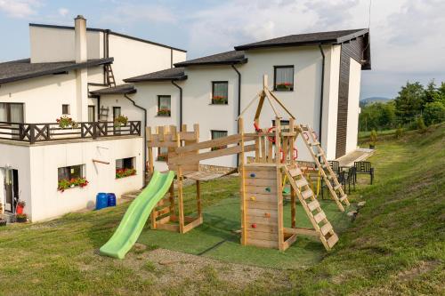 um parque infantil em frente a uma casa com escorrega em Vale Humor Residence em Mănăstirea Humorului