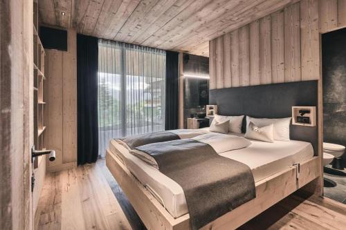 een slaapkamer met een groot bed en een groot raam bij Waldchalet mit Jacuzzi in Racines