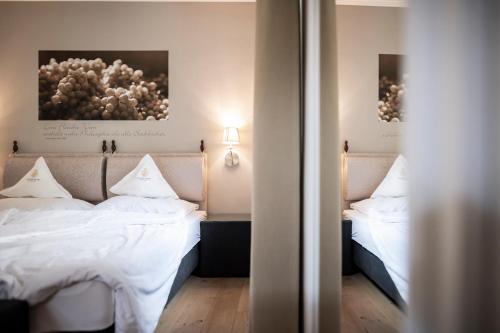 a bedroom with two beds with white sheets at Schloss Plars wine & suites in Lagundo