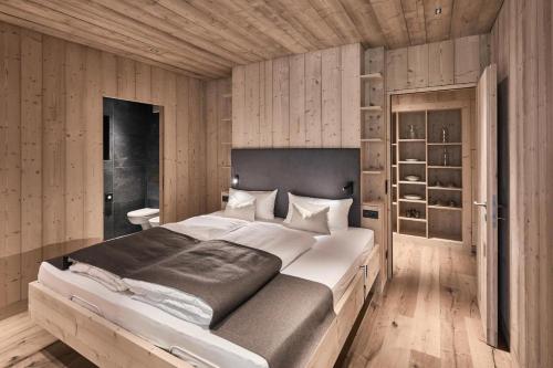 a bedroom with a large bed and wooden walls at Ruhiges Waldchalet in Racines