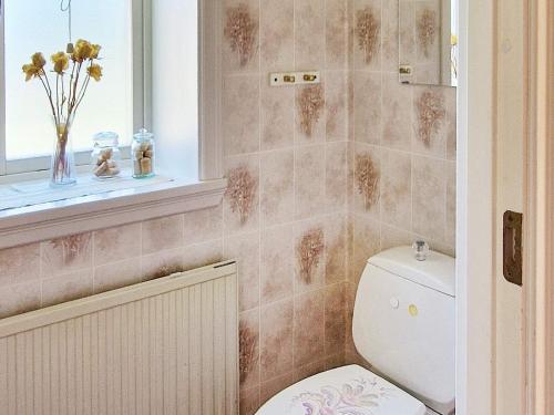 La salle de bains est pourvue de toilettes, d'une fenêtre et d'un vase de fleurs. dans l'établissement Holiday home LJUSDAL IV, à Ljusdal