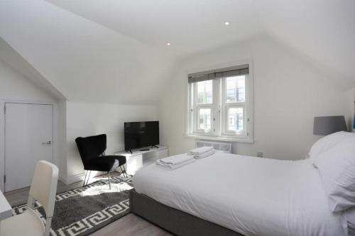 a white bedroom with a bed and a desk and a chair at The Stafford Apartments in Bournemouth