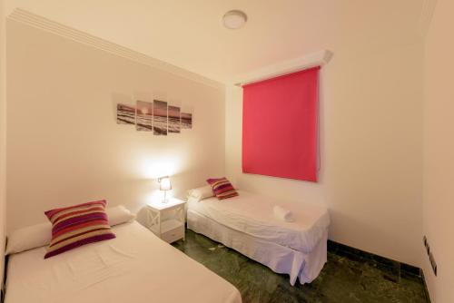 2 letti in una camera con finestra rossa di Apartamento Céntrico Sibarys-3 dormitorios a Nerja