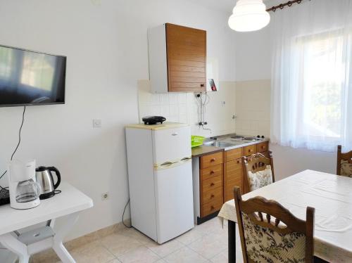 a small kitchen with a white refrigerator and a table at Apartments Lidija in Lopar