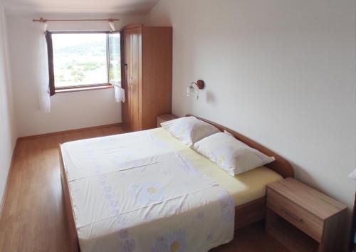 a small bedroom with a bed and a window at Apartments Lidija in Lopar