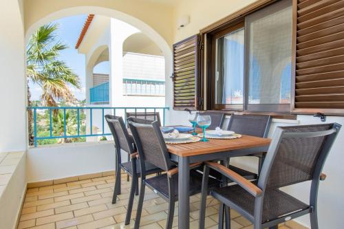 a dining room with a table and chairs and a balcony at Monte Dourado in Carvoeiro