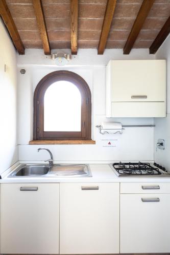 a kitchen with white cabinets and a sink and a window at Rustic House, con patio e giardino, Assisi centro in Assisi
