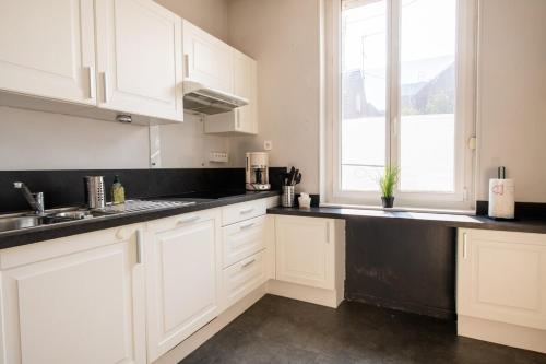 une cuisine avec des armoires blanches et un comptoir noir dans l'établissement Maison cosy 4 chambres, terrasse, garage privé, à Croix