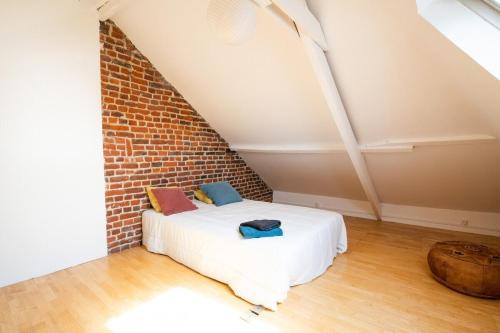 un lit dans une chambre avec un mur de briques dans l'établissement Maison cosy 4 chambres, terrasse, garage privé, à Croix