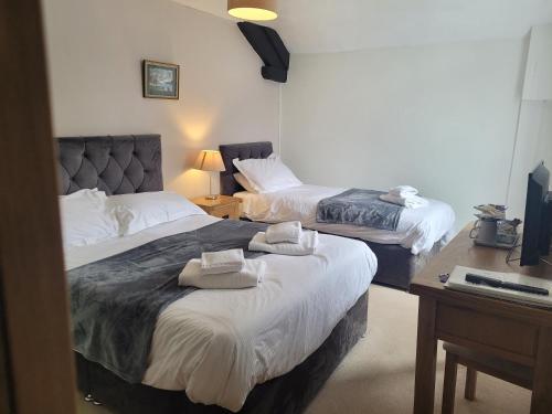 two beds in a hotel room with towels on them at Bower House Inn in Eskdale