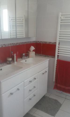 La salle de bains est pourvue d'un lavabo blanc et d'un mur rouge. dans l'établissement Maison moderne 3 chambres 6 mns plage, à Lorient