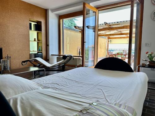 1 dormitorio con 1 cama, 1 silla y balcón en Fantastica terrazza con solarium e infernot by Revenue House, en Vignale