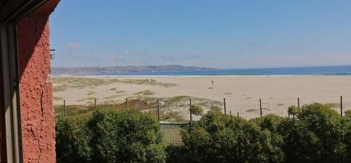 a view of a beach with a fence and the ocean at Condominio Ilimay Las Cruces in Las Cruces