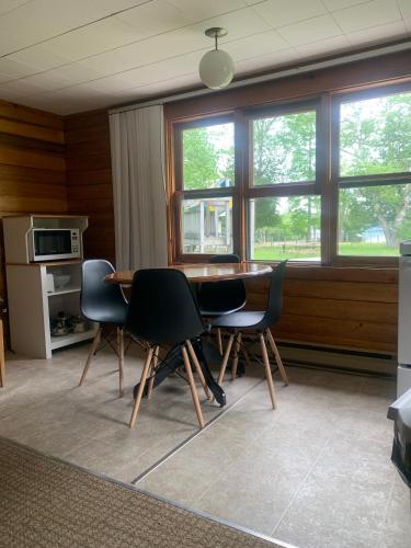 a dining room with a table and chairs and windows at Colonial Bay Motel and Cottages in Huntsville