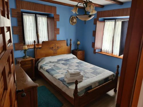 a bedroom with a bed with blue walls and windows at El BurbyI in Somo