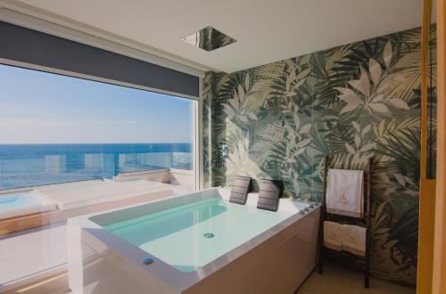 a bathroom with a tub and a large window at Parco dei Principi - Resort & Spa in Torre San Giovanni Ugento