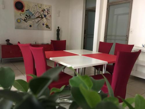 a dining room with red chairs and a table at Le Limas in Avignon