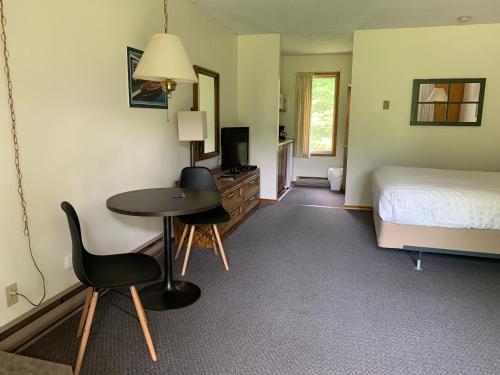 a bedroom with a bed and a table and a desk at Colonial Bay Motel and Cottages in Huntsville