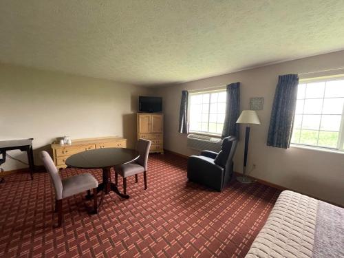 ein Hotelzimmer mit einem Tisch, Stühlen und einem Bett in der Unterkunft The Woodridge Inn in Connersville