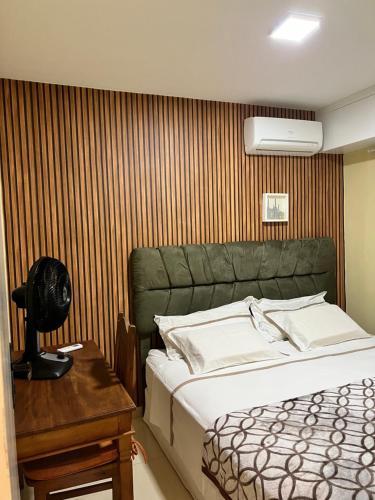 a bedroom with a bed and a desk with a fan at Apartamento aconchegante. in Petrolina