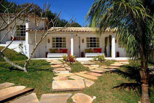 a house with a palm tree and a stone walkway at Pousada Bucaneiro in Búzios