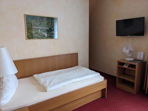 a small bedroom with a bed and a television at Weinhaus Berg in Bremm
