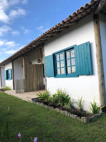 uma casa com persianas azuis e um quintal em Vila Aratu Corumbau em Corumbau